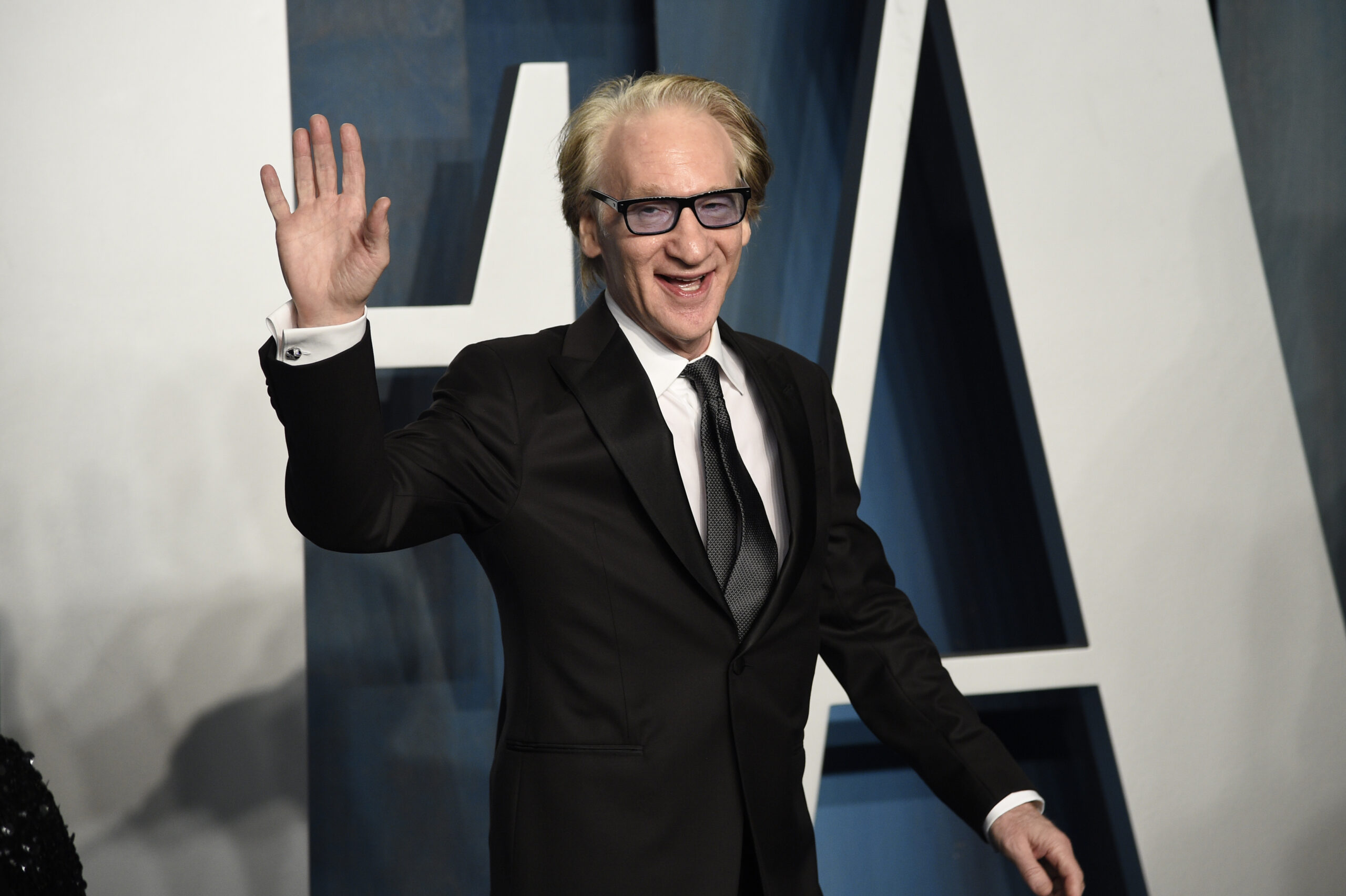 Bill Maher in a suit waving as he arrives at 2022 Oscars after party